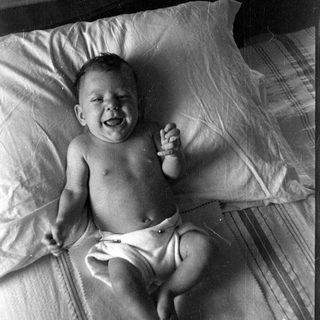 Infant in a diaper lying on a bed.
