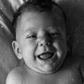 Infant in a diaper lying on a bed.