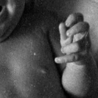 Infant in a diaper lying on a bed.
