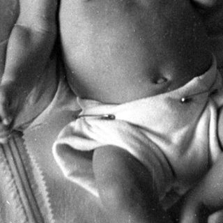 Infant in a diaper lying on a bed.