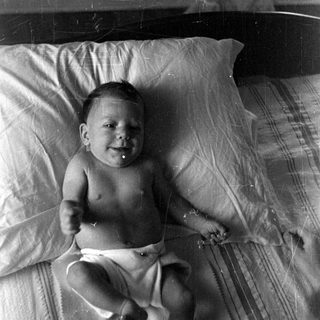 Infant in a diaper lying on a bed.