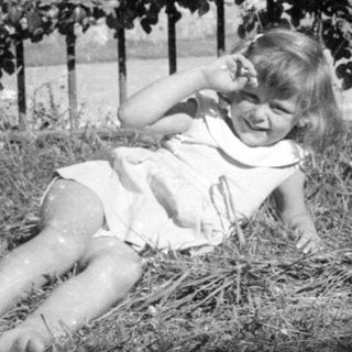 Young girl in a dress lying in dry grass.