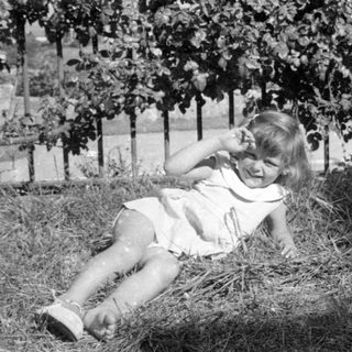 Young girl in a dress lying in dry grass.