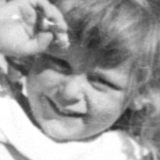 Young girl in a dress lying in dry grass.