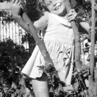 Young girl in a dress standing among trees.