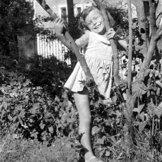 Young girl in a dress standing among trees.