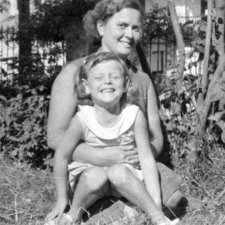 Woman and young girl sitting outdoors in a garden.