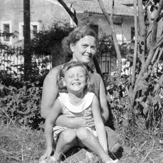 Woman and young girl sitting outdoors in a garden.