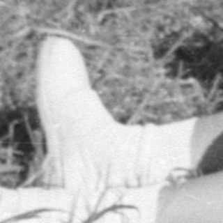 Young girl in white dress sitting outdoors.