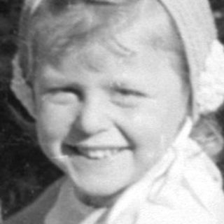 Young girl in white dress sitting outdoors.