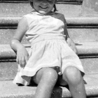 Young girl in sun hat sitting on stone steps.