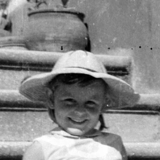 Young girl in sun hat sitting on stone steps.