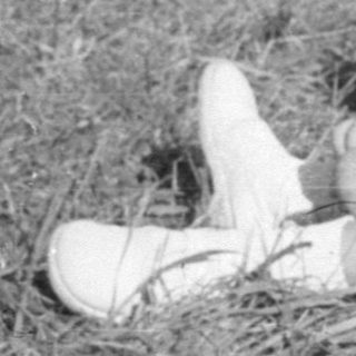 Young girl in white dress sitting on grass.