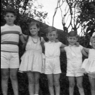 Six children standing in a row outdoors.