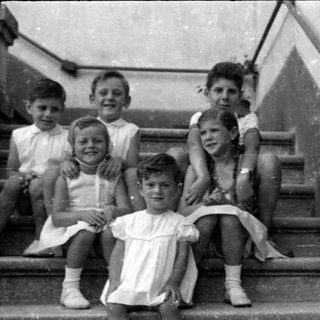 Six children posed on concrete stairs.