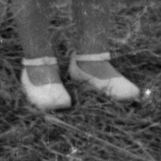 Young child in a white dress standing outdoors.
