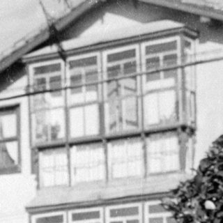 Girl in white dress standing before a house.