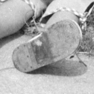 Child in sun hat holding a doll outdoors.