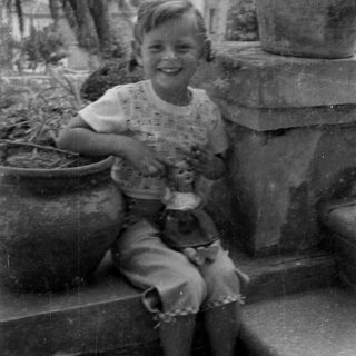 Smiling child holding a doll outdoors.