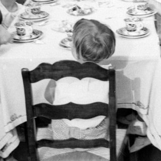 Outdoor meal with adults and children under palm tree.