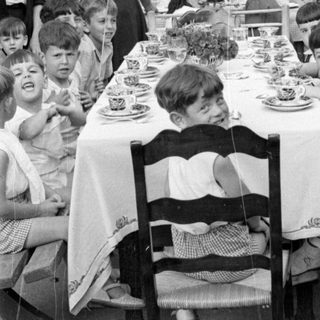 Children and adults at an outdoor dining table.