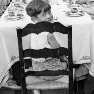 Children and adults at an outdoor dining table.