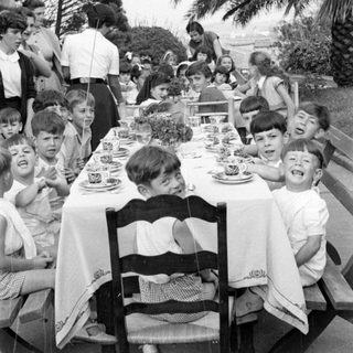 Children and adults at an outdoor dining table.