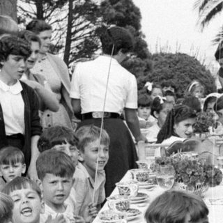 Children and adults at an outdoor dining table.