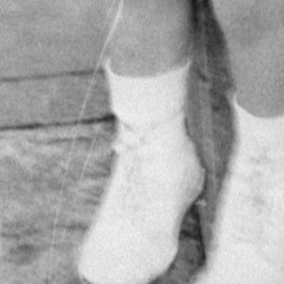 Young child in white clothing sitting on concrete.