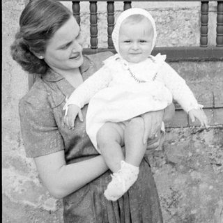 Woman holding a baby in a white bonnet.
