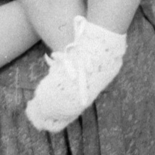 Woman holding a baby in a white bonnet.