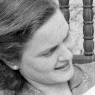 Woman holding a baby in a white bonnet.