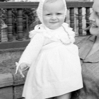 Woman and child in white dress by a railing.