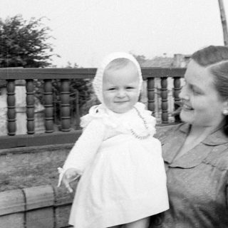 Woman and child in white dress by a railing.