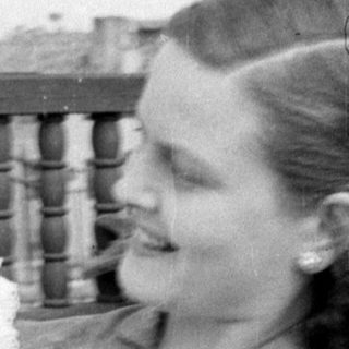 Woman and child in white dress by a railing.
