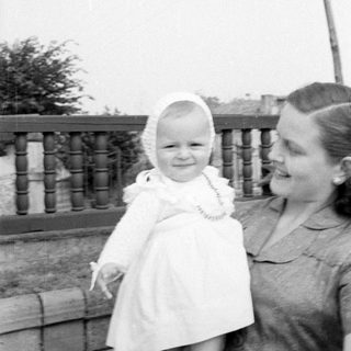Woman and child in white dress by a railing.