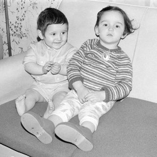 Two young children sitting on a sofa.