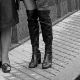 Two women standing on a bridge beside a car.