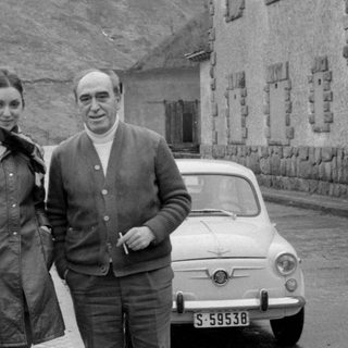 Couple with a Fiat 500 by a rocky hill.