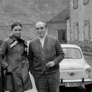 Couple with a Fiat 500 by a rocky hill.