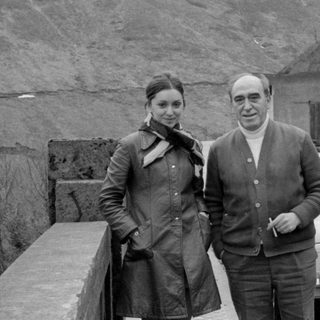 Couple with a Fiat 500 by a rocky hill.