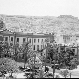 Cityscape with neoclassical building and hillside housing.