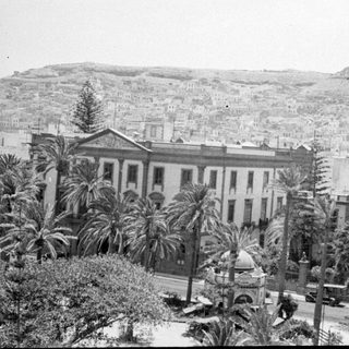 Cityscape with neoclassical building and hillside housing.