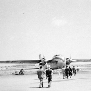 People walking toward a twin-engine propeller plane.