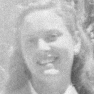 Woman in a skirt suit holding a small animal.