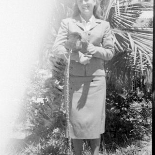 Woman in a skirt suit holding a small animal.