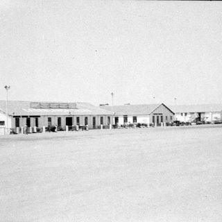 Row of white buildings on a flat plain.