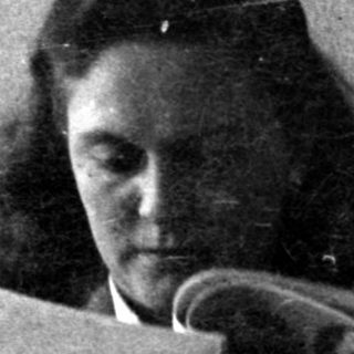Woman reading a booklet on a leather sofa.