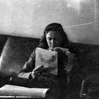 Woman reading a booklet on a leather sofa.