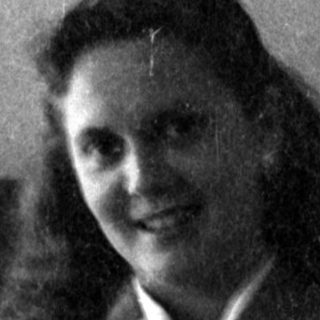 Woman in a blazer sitting on a leather sofa.